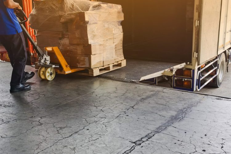 Worker driving forklift loading and unloading shipment carton bo